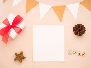 Christmas composition with gift, white paper blank, pine cones, flags. Flat lay, top view, copy space