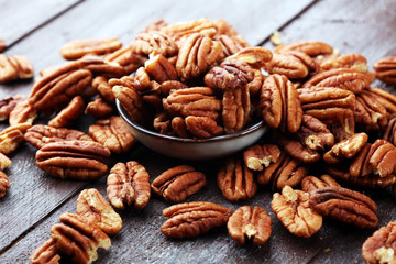 Pecan nuts on a rustic wooden table and pecan nuts in bowl - obrazy, fototapety, plakaty