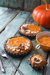 Homemade vegetarian sweets. Pumpkin puree and open pumpkin pies on shabby blue background