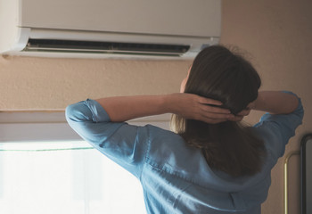 Women dying from the heat standing in front of the air conditioner.