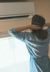 Women dying from the heat standing in front of the air conditioner.