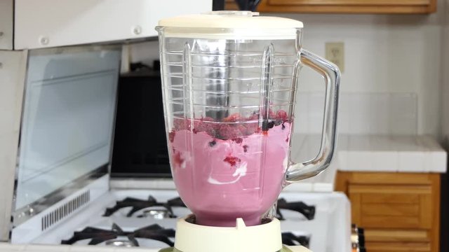 Vintage blender making smoothie time lapse.  Residential kitchen with vintage stove top in background.