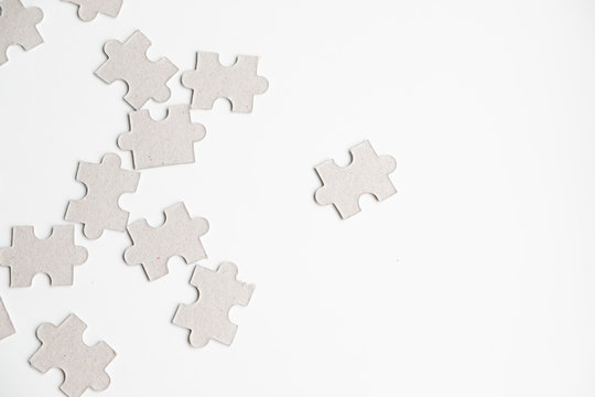 Unfinished white jigsaw puzzle pieces on white background