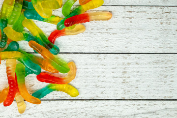 Pile of colorful gummy worms on a wooden background