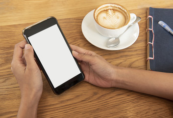 hand holding mobile phone with blank white screen in cafe. mockup advertising.