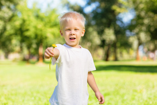 Little man. Excited cute child looking at you while holding a flower