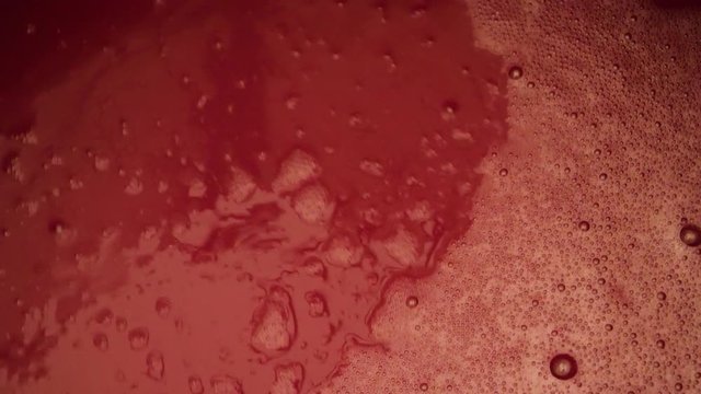Close-up looking into a vat of red wine at a wine factory in preparation for bottling