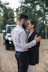 Newlyweds near a black car for a walk in the forest