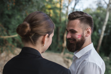 The girl left a print from the lipstick on the guy's cheek while walking in the woods