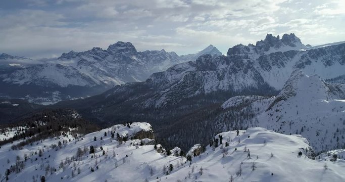 Forward aerial to snowy alpine valley with woods forest at Cinque Torri.Sunny sunset or sunrise,sunny day,cloudy sky.Winter Dolomites Italian Alps mountains outdoor nature establisher.4k drone flight