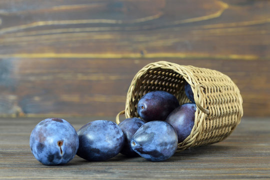 Fresh plums in the basket on wooden background