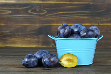 Bowl of fresh plums on wooden background