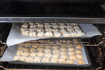 Dirty oven with two trays of star shaped cinnamon Christmas cookies - glazed and unglazed