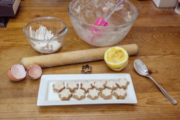 Swiss or German style cinnamon star shaped Christmas cookies known as Zimtsterne with some of the ingredients on messy kitchen bench