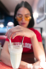 Portrait of brunette sitting in dinner with yellow sunglasses and red tshirt with overlook print