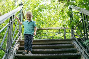 Fototapeta na wymiar A little boy goes down the stairs in the forest.