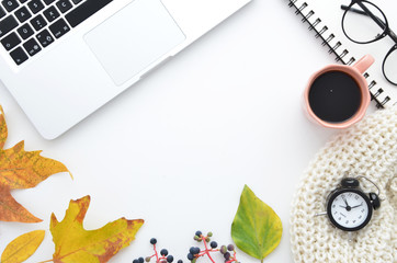 Workspace with laptop, planner, coffee cup, glasses and dry autumn leaves, alarm clock. Stylish office desk. Autumn or Winter concept. Flat lay, top view