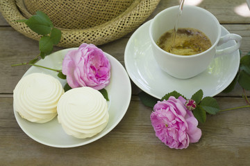 Preparation of instant coffee on a rustic wooden table where there is a marshmallow for dessert, rose flowers and a summer lady hat is a breakfast in the village on a summer morning.