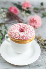 Cup with cappuccino, doughnut, pink pastel giant blanket, flowers, bedroom, morning concept