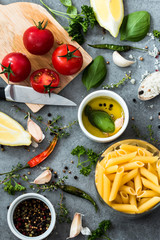 Raw Pasta with ingredients on grey background