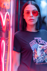 Portrait of brunette girl in neon red lights and red sunglasses