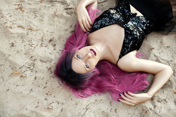 Obraz na płótnie Canvas Young sensual woman laying on beach in black dress