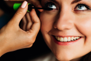 Obraz premium close-up of the face of the bride with a beautiful smile. Makeup artist applied mascara on the eyelashes