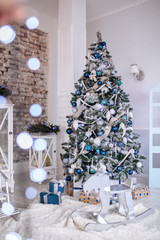 Christmas and New Year decorated interior room with presents and New year tree and toy wooden deer close up. Copy space