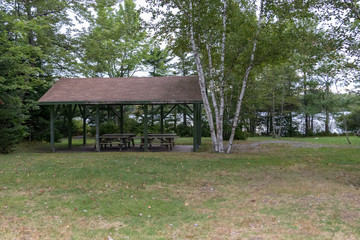 Wooden shelter with picnic tables in park, overcast day, lewis lake, nova scotia, canada