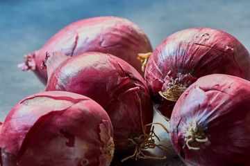 group of fresh red onions on a gray kitchen desk