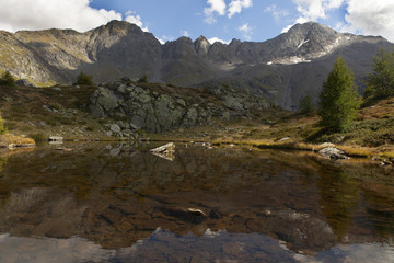 Fototapeta na wymiar riflesso del pizzo stella a destra della foto in piccolo laghetto di montagna