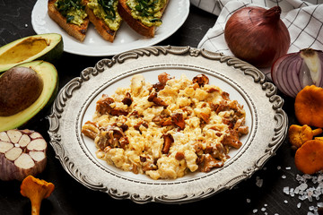 delicious scrambled eggs with chanterelles straight from the forest on a plate and bread with avocado