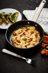 delicious scrambled eggs with chanterelles straight from the forest in a pan and bread with avocado on a wooden kitchen table