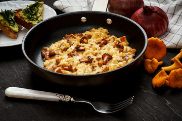 delicious scrambled eggs with chanterelles straight from the forest in a pan and bread with avocado on a wooden kitchen table