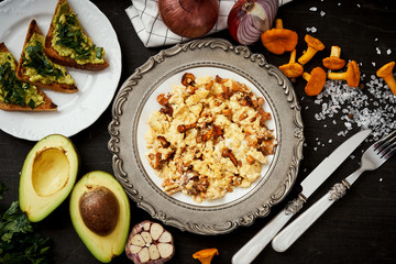 delicious scrambled eggs with chanterelles straight from the forest on a plate and bread with avocado