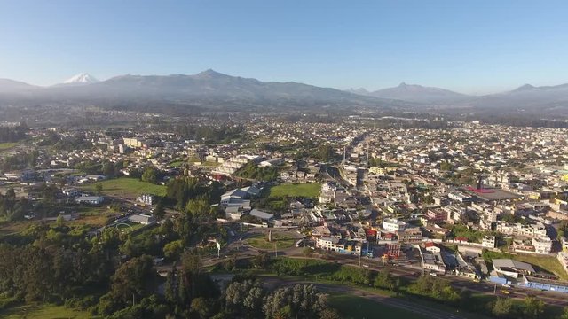 Aerial pan over Sangolqui, Ecuador. In the Inter-Andean valley near Quito, Ecuador. Many volcanoes in background, including snowcapped Cotopaxi. 