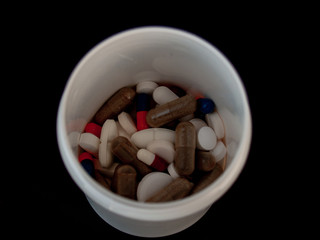 A pot of pills of different sizes, shapes and colors. Health concept