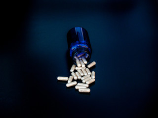 A pot of pills with black background. Health concept