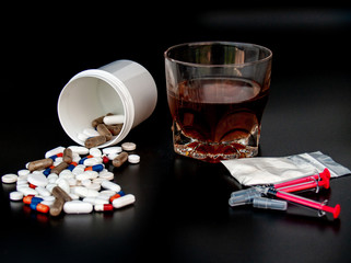 Pills of different sizes, shapes and colors, a glass of whiskey, drugs and syringes Concept of drugs and alcohol