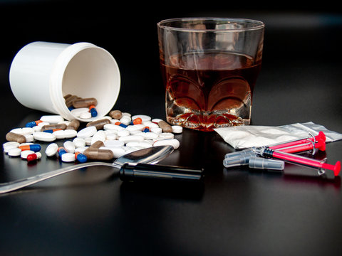 Pills of different sizes, shapes and colors, a glass of whiskey, drugs and syringes Concept of drugs and alcohol