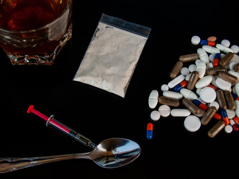 Pills of different sizes, shapes and colors, a glass of whiskey, drugs and syringes Concept of drugs and alcohol