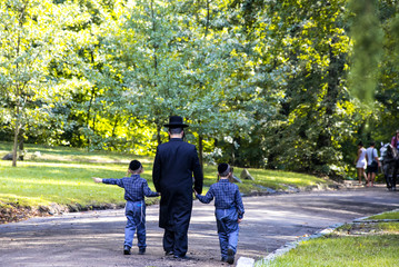 A family of Hasidic Jews, a man with children, walks through the Autumn Park in Uman, Ukraine, during the Jewish New Year,  Religious Orthodox Jew © rospoint