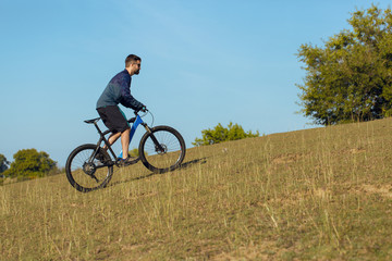 A cyclist rides the hills, Beautiful portrait of a guy on a blue bicycle