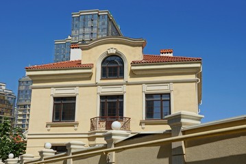 part of a private brown house with windows behind a fence against the blue sky