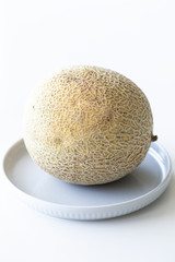 Cantaloupe or melon sitting on blue plate on white background