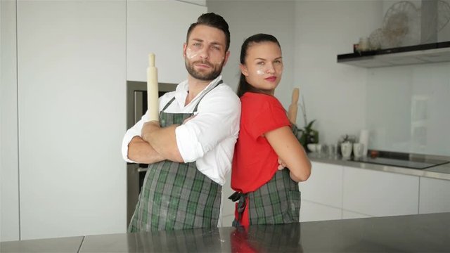 Horizontal Portrait of Surprised Female Leans At Husbands Shoulder Being Shocked That He Is Not Tired After Helping To Prepare Pizza, Has Confidence And Strength. Couple Work As Team On Kitchen.