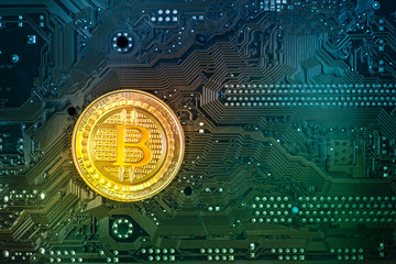 Gold bitcoin coin on a colorful circuit board. Blue-green background