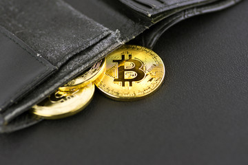 bitcoin coin in a black wallet on a simple matte black background