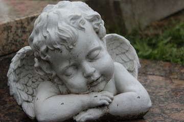 Putto, schlafende Engelfigur auf einem Grab