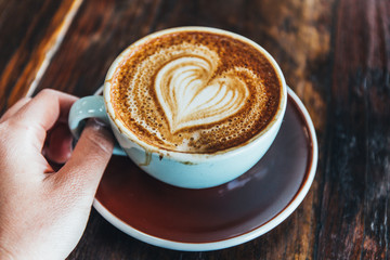 holding cup of coffee with cream on white background 